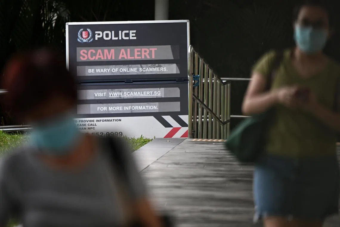 People walking past a Police Scam Alert signage near the Bishan Junction 8 shopping mall on Aug 18, 2022.
