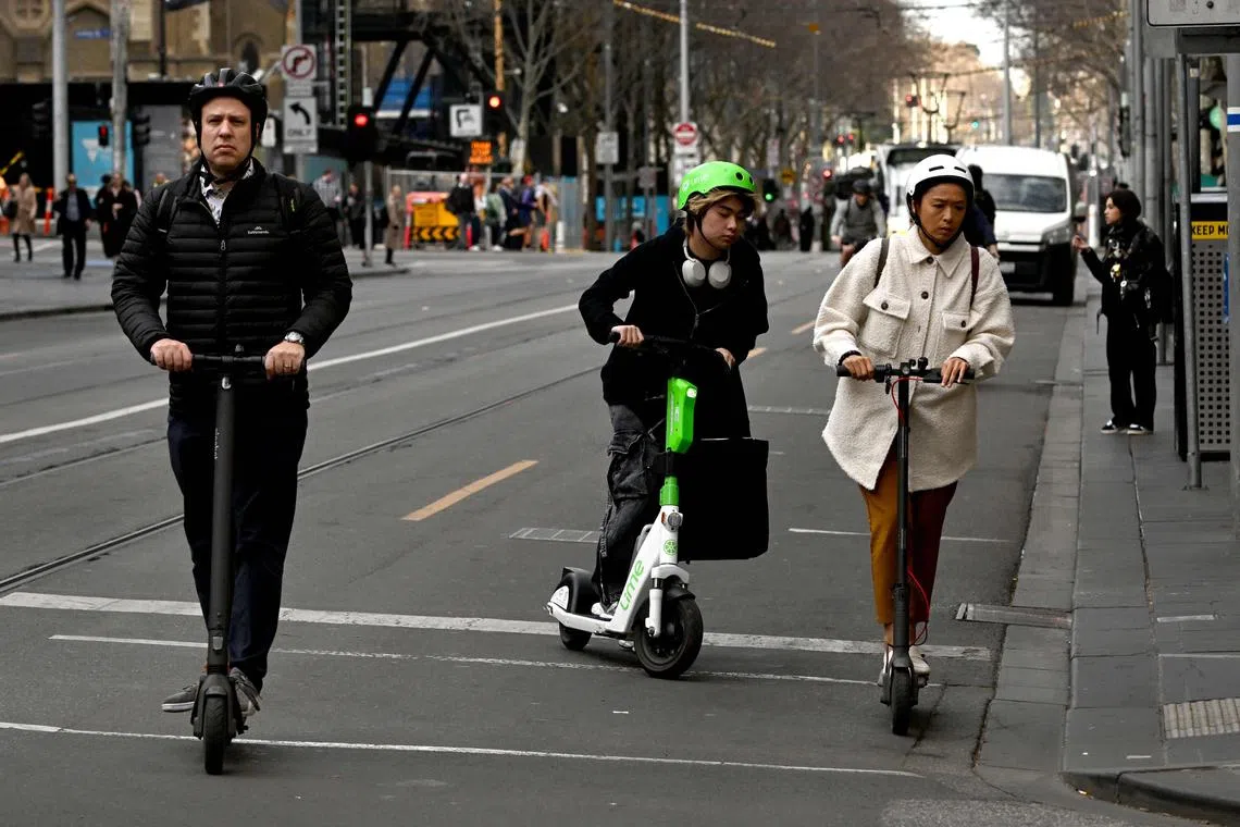 People ride e-scooters in Melbourne's central business district (CBD) on August 14, 2024. The City of Melbourne council will ban the hire e-scooters from the city's CBD citing safety concerns due to the bad behaviour of riders not wearing helmets, riding on footpaths, carrying more than one passenger, leading to over 860 collisons and seven fatalities in the past three years. (Photo by William WEST / AFP)