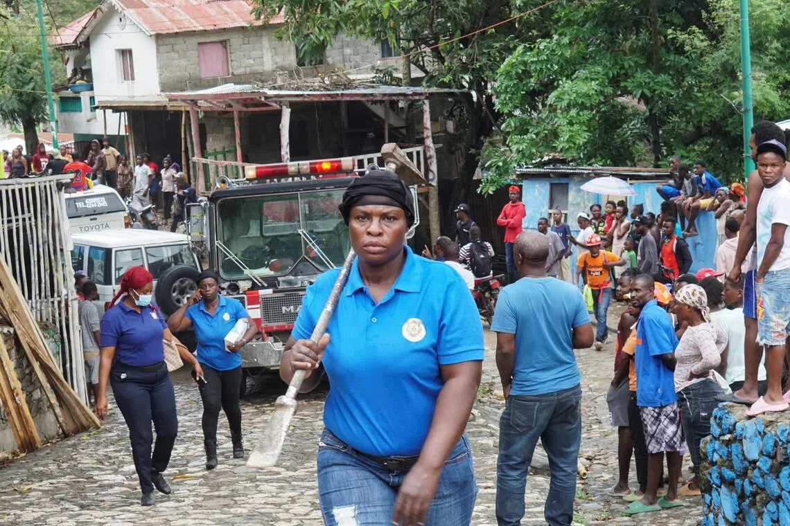 A rescue worker carries a tool at the site after Haiti's Civil Protection for the Nord Department said a stampede killed several people at the Laferriere Citadel.