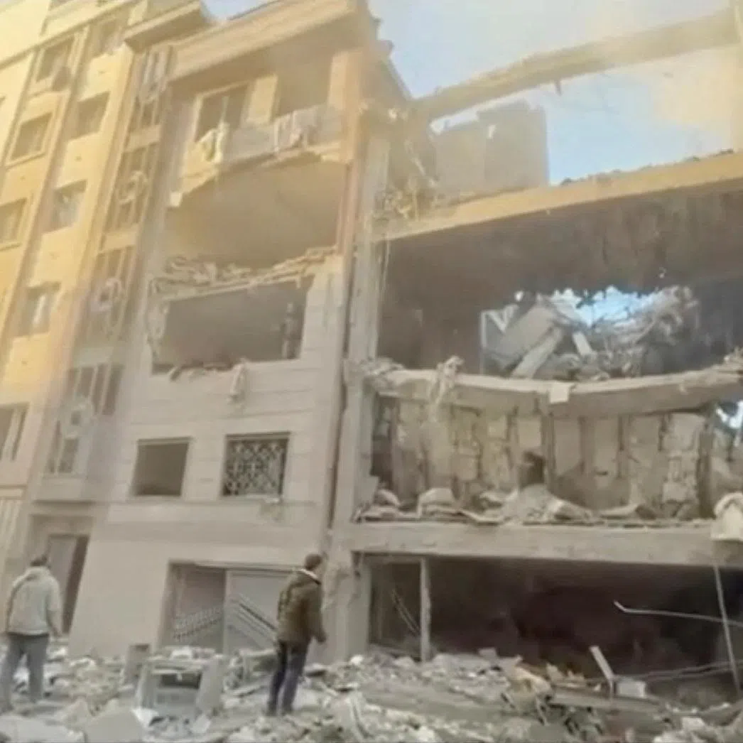People stand near damaged buildings, amid the U.S.-Israeli conflict with Iran, in Tehran, Iran, in this still image obtained from a handout video released on April 1, 2026.    Iranian Red Crescent Society/Handout via REUTERS