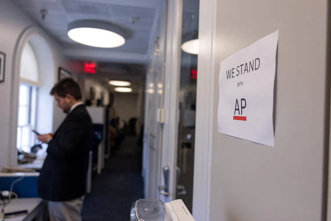 FILE PHOTO: A journalist looks at his mobile phone next to a sign which reads, \"We Stand with AP\", a reference to the case between the Associated Press and the White House, during the press briefing by White House Press Secretary Karoline Leavitt at the White House in Washington, D.C., U.S., March 26, 2025. REUTERS/Carlos Barria/File Photo