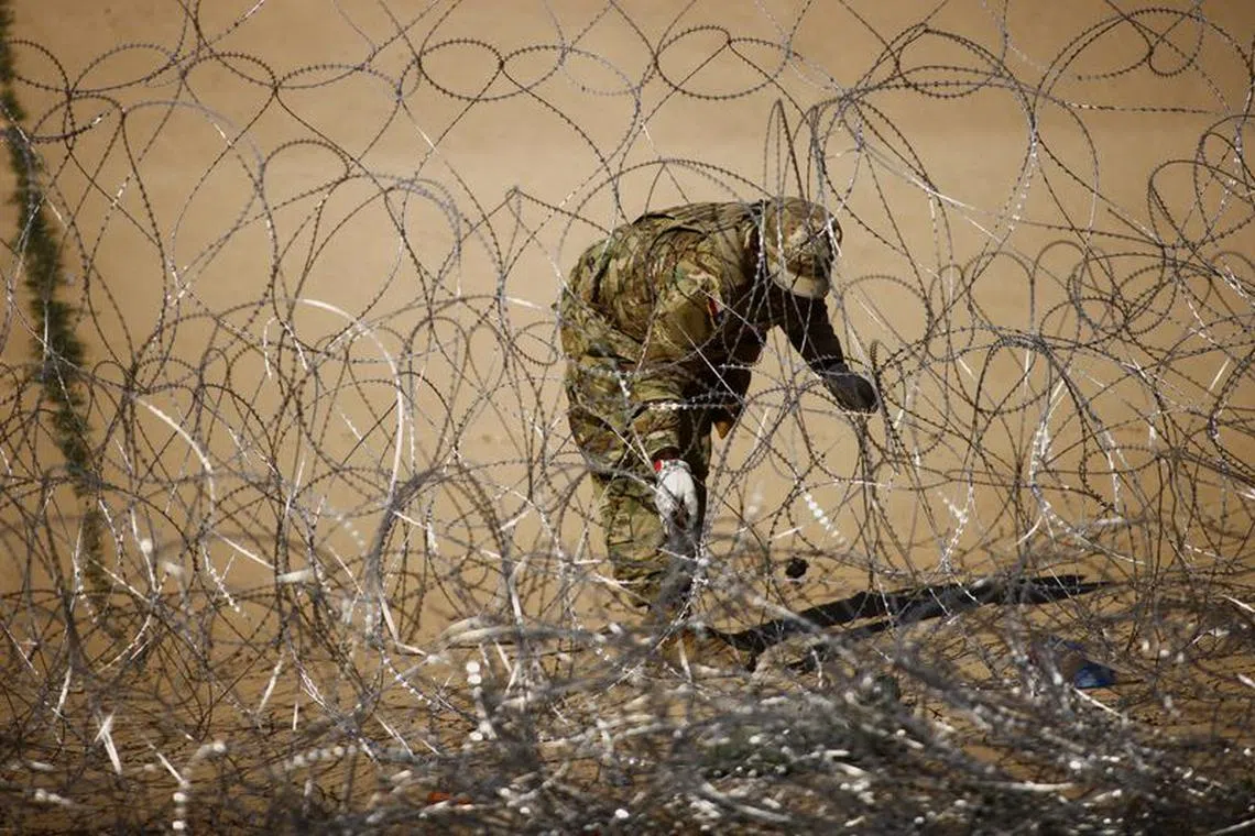 A member of the Texas National Guard works on a razor wire fence, near a border wall on the banks of the Rio Bravo River, on the border between the U.S. and Mexico, as seen from Ciudad Juarez, Mexico September 18, 2023. REUTERS/Jose Luis Gonzalez/ File Photo