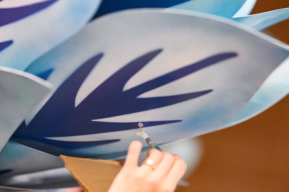 ST20260807-202639200847-Lim Yaohui-yhpeili/ Paper artist Koh Pei Li painting to cover up scuff marks on the floral sculpture made during transportation process to ACM for installation on Aug 7, 2026. Paper artist Pei Li has been invited to participate in Homo Faber 2026 in Venice, one of the world's leading exhibitions celebrating exceptional craftsmanship. Taking place during the same period as the Venice Biennale, Homo Faber brings together master artisans from around the world. During the invitation only opening program from 28 to 31 August, Pei Li will be presenting a live demonstration of her craft and exhibiting one of her botanical sculptures, before the exhibition opens to the public on 1 September. The floral sculptures from her installation at Cavenagh Bridge for ACM are currently being repurposed and will be relocated as a permanent installation within ACM, with the installation expected in late July or early August. Around the same time, she will also be creating this year's Lilytopia floral installations for Gardens by the Bay before travelling to Venice at the end of August for Homo Faber. (ST PHOTO: LIM YAOHUI)