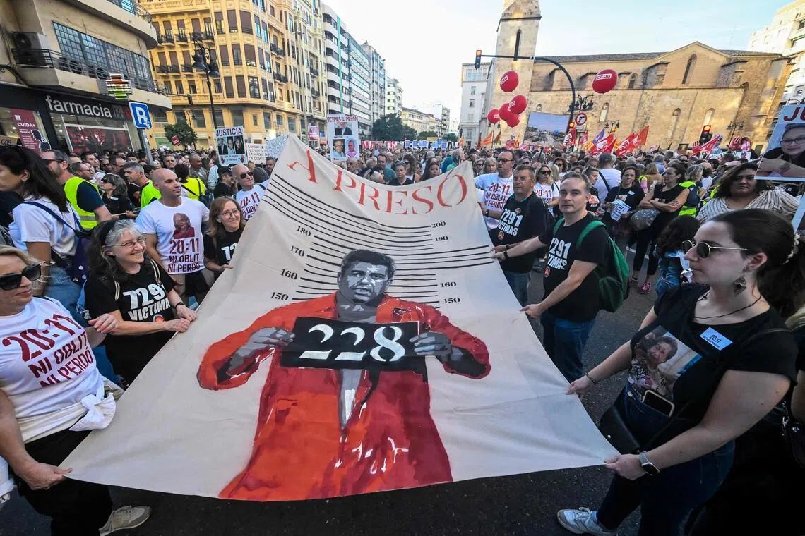 Protesters in Valencia hold up a banner depicting regional president Carlos Mazon, during a march in Valencia on Oct 25 to mark the anniversary of flooding that resulted in the deaths of 229 people.