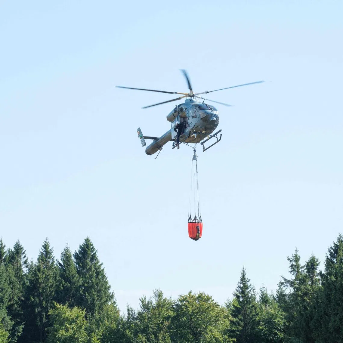 A Belgian police helicopter preparing to drop water over a wildfire in Belgium’s High Fens nature reserve on Aug 14.