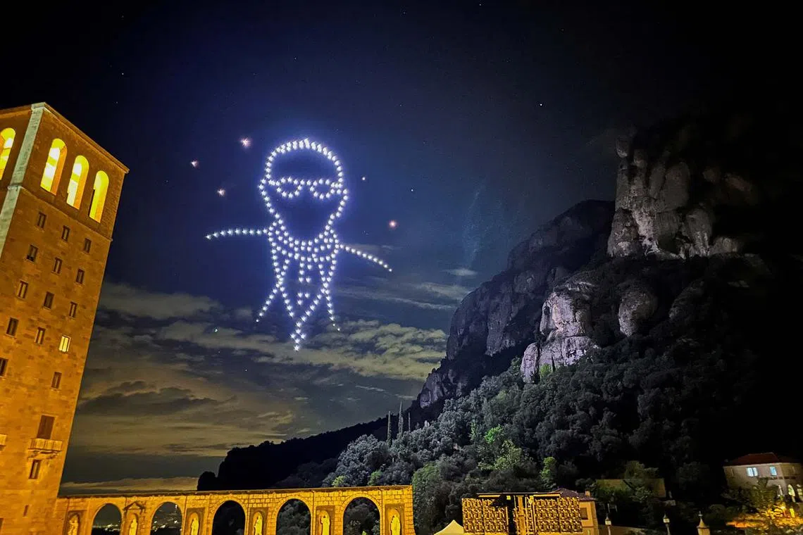 Locals and tourists looking at drones lighting the sky, creating an image of the late Pope Francis, by Flock Drone Art, on the Montserrat Abbey, to mark 1000th anniversary of its foundation, in Montserrat, near Barcelona, Spain, April 27, 2025. 