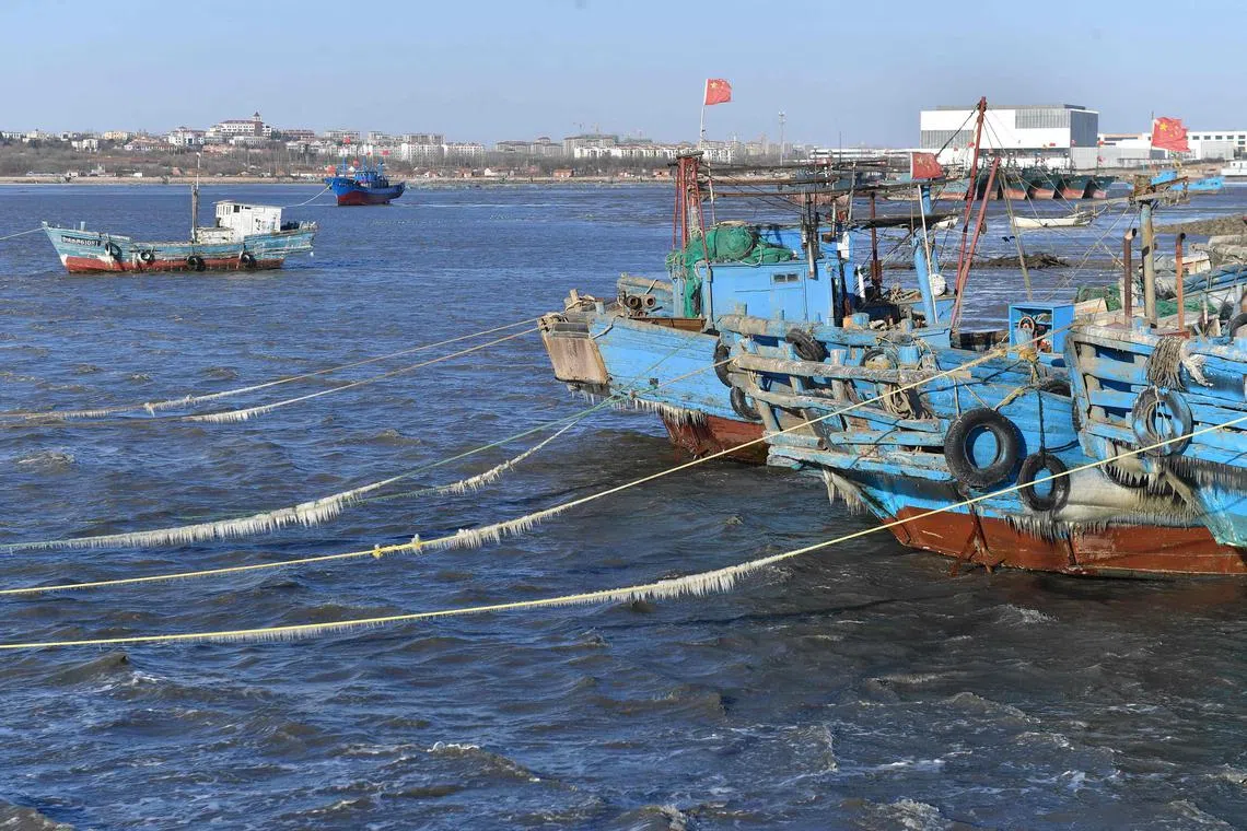 This photo taken on December 17, 2022 shows fishing boats on the frozen sea in Qingdao, in China's eastern Shandong province. (Photo by AFP) / China OUT