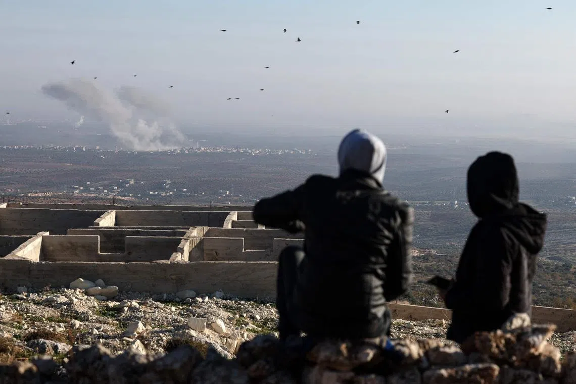 In this picture taken from the northern Syrian village of Ariha, people watch as smoke billows from the site of clashes between Syrian anti-government fighters and regime forces on the outskirts of the city of Saraqib, in Syria's Aleppo province, on Nov 28.