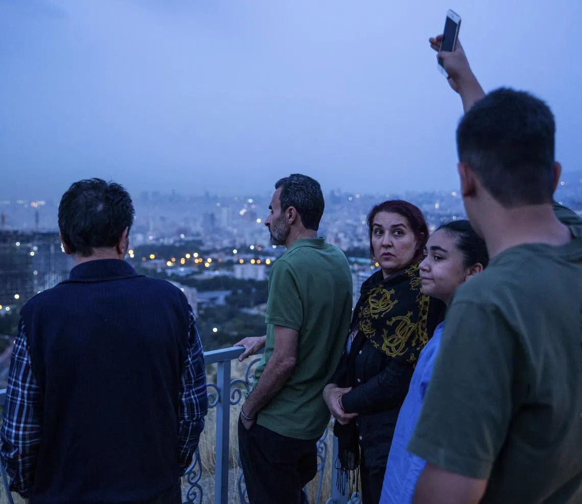 People watch smoke rise in Tehran, Iran, on June 13, 2025. Explosions rocked Tehran early Friday morning, as Israel carried out a major attack on Iran intended to cripple the country’s nuclear program, Israeli officials said. (Arash Khamooshi/The New York Times)