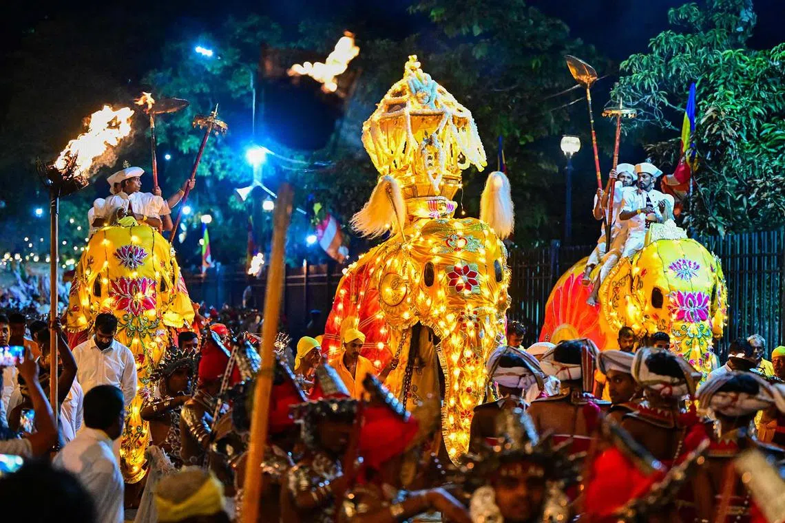 TOPSHOT - Decorated elephants walk past the historic Buddhist Temple of the Tooth as part of celebrations to mark the Buddhist festival of Esala Perahera, in the ancient hill capital of Kandy, on August 19, 2024. (Photo by Ishara S. KODIKARA / AFP)