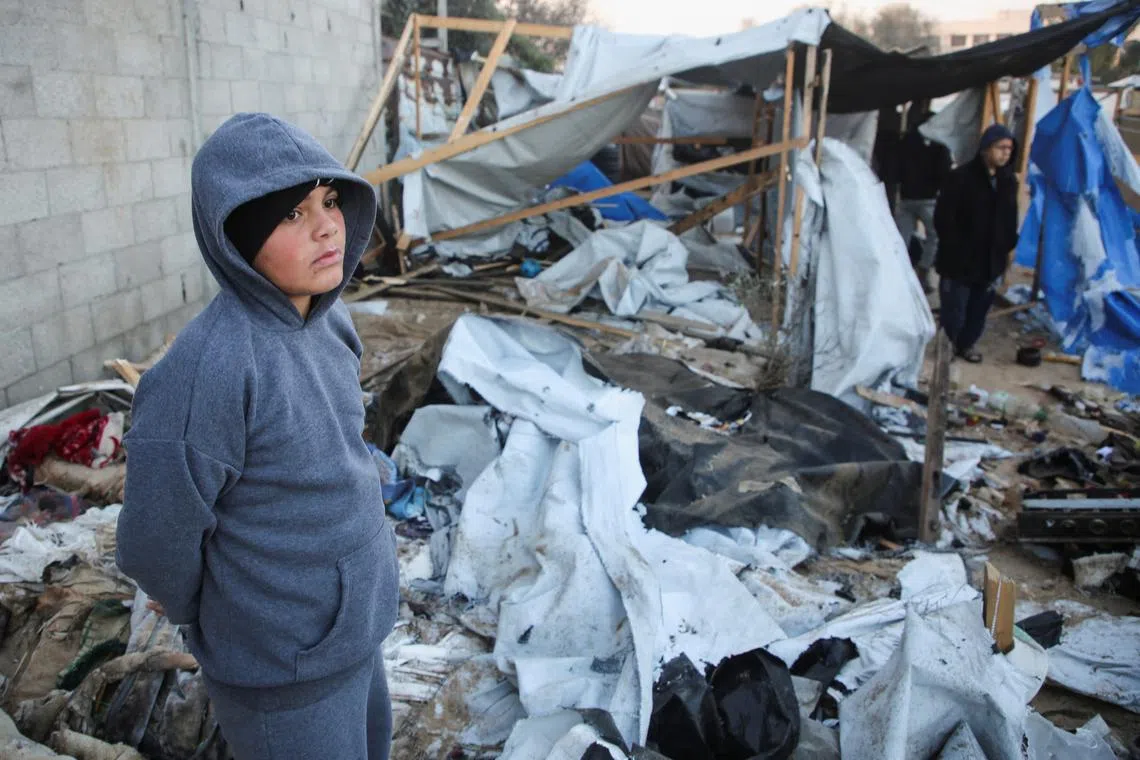 A Palestinian boy stands amidst the damage at a tent camp sheltering displaced people, following an Israeli strike, amid the Israel-Hamas conflict, in Al-Mawasi area, in Khan Younis, southern Gaza Strip, December 18, 2024. REUTERS/Hatem Khaled