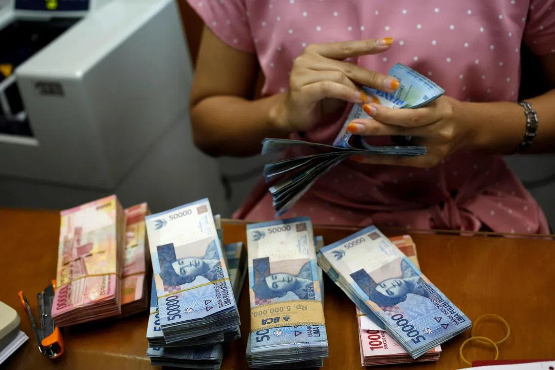 A teller counts Indonesian rupiah bank notes at a money changer in Jakarta on Aug 13, 2018.