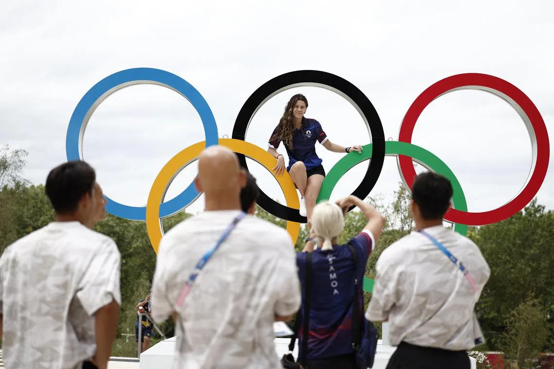 An athlete poses on the Olympic rings in the Olympic village, ahead of the Paris 2024 Games.