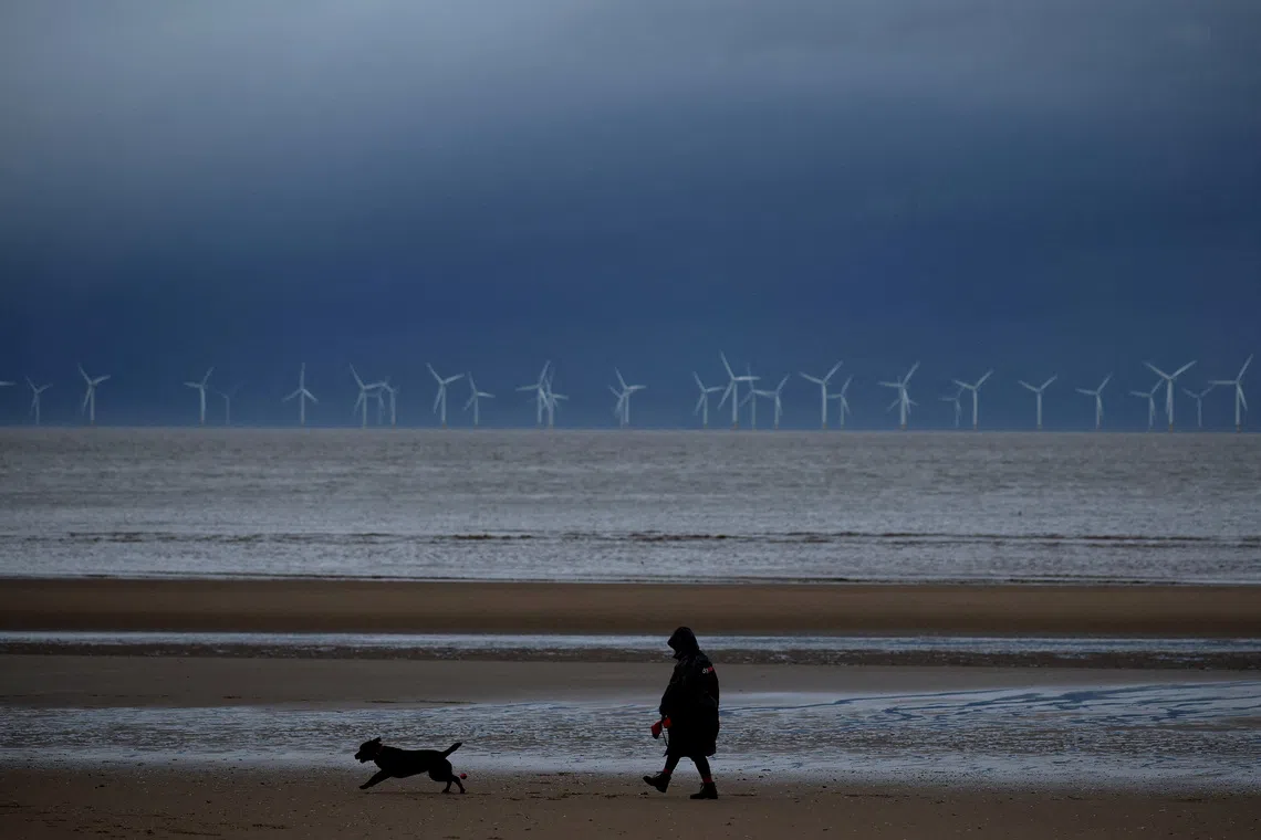 A woman walking her dog beneath dark skies on the beach, as Storm Bram approaches New Brighton, in Britain, on Dec 9, 2025. 
