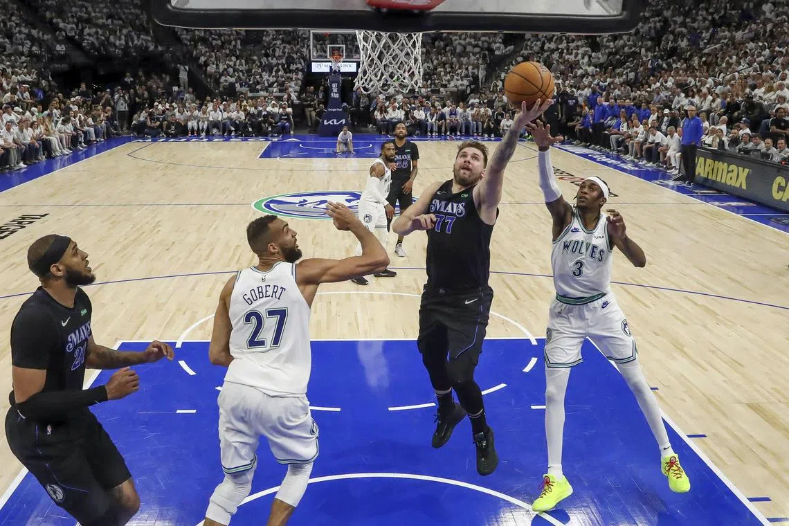 Dallas Mavericks guard Luka Doncic shoots against Minnesota Timberwolves forward Jaden McDaniels and centre Rudy Gobert in the second half of Game 2 of the NBA Western Conference Finals.