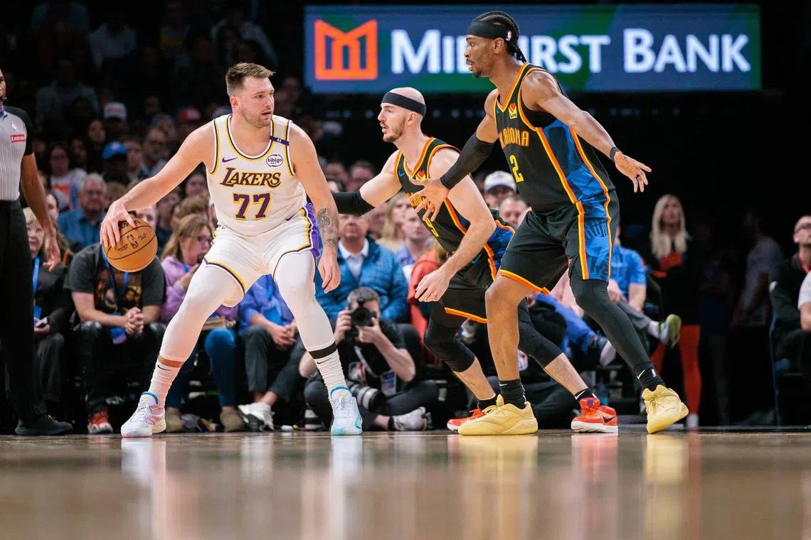 Luka Doncic of the Los Angeles Lakers drives to the basket around Shai Gilgeous-Alexander and Alex Caruso of the Oklahoma City Thunder during the first quarter at Paycom Centre.