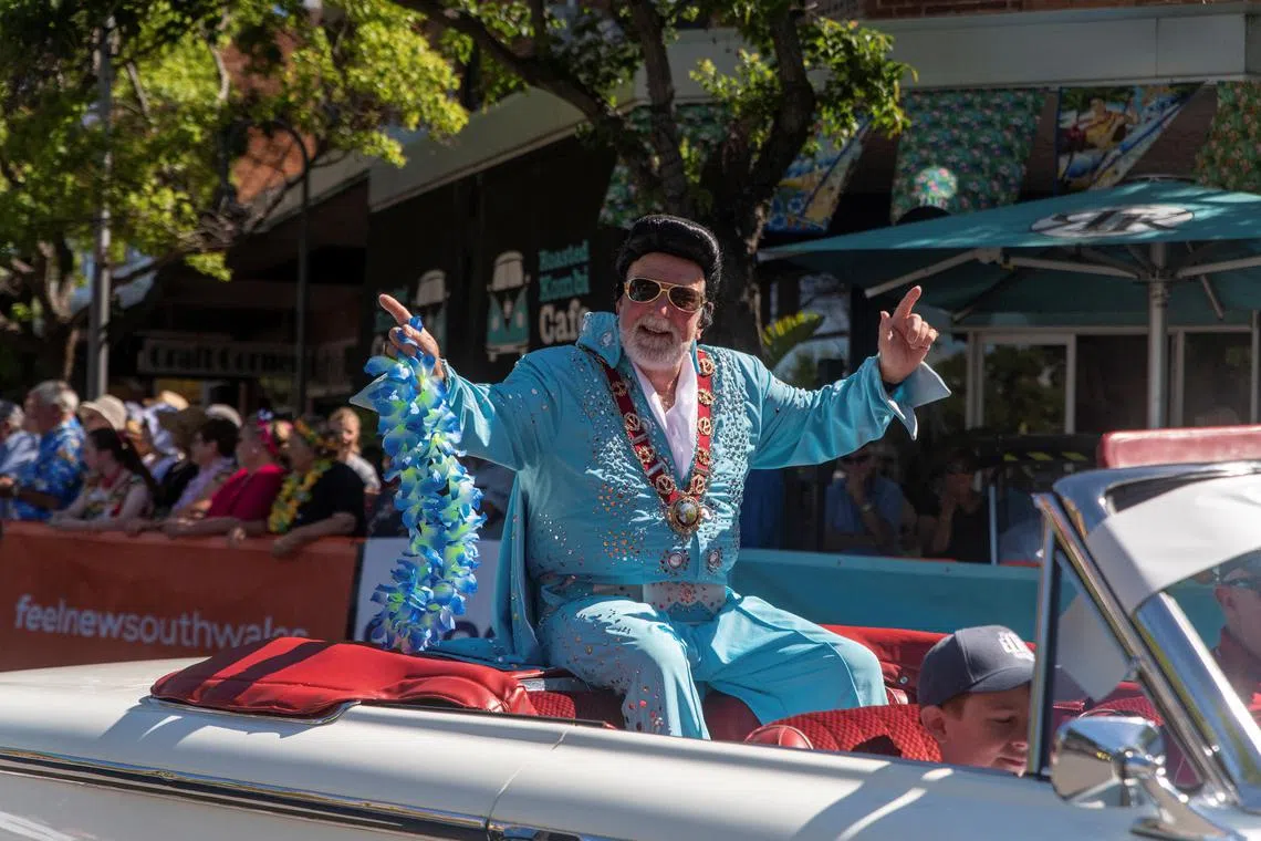 Parkes Mayor Ken Keith, dressed as Elvis Presley, sits on top of a car at the Parkes Elvis Festival parade in Parkes, Australia.