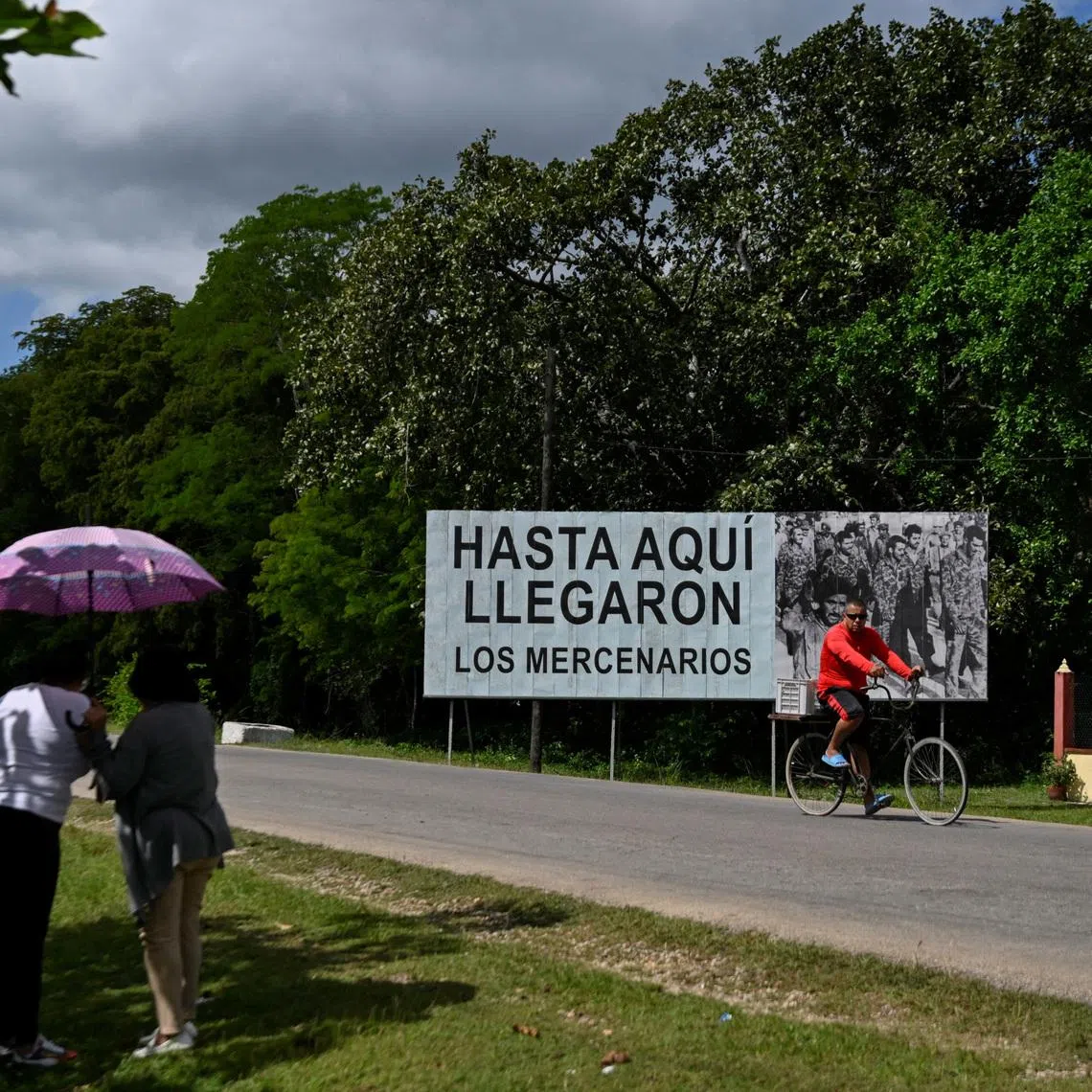 Two women connect to the internet near a billboard reading \"The mercenaries reached this far\" as Cuba marks the 65th anniversary of its victory over the CIA-backed Bay of Pigs invasion, amid a U.S. oil blockade and threats from U.S. President Donald Trump, in Palpite, Cienaga de Zapata, Cuba April 7, 2026. REUTERS/Norlys Perez