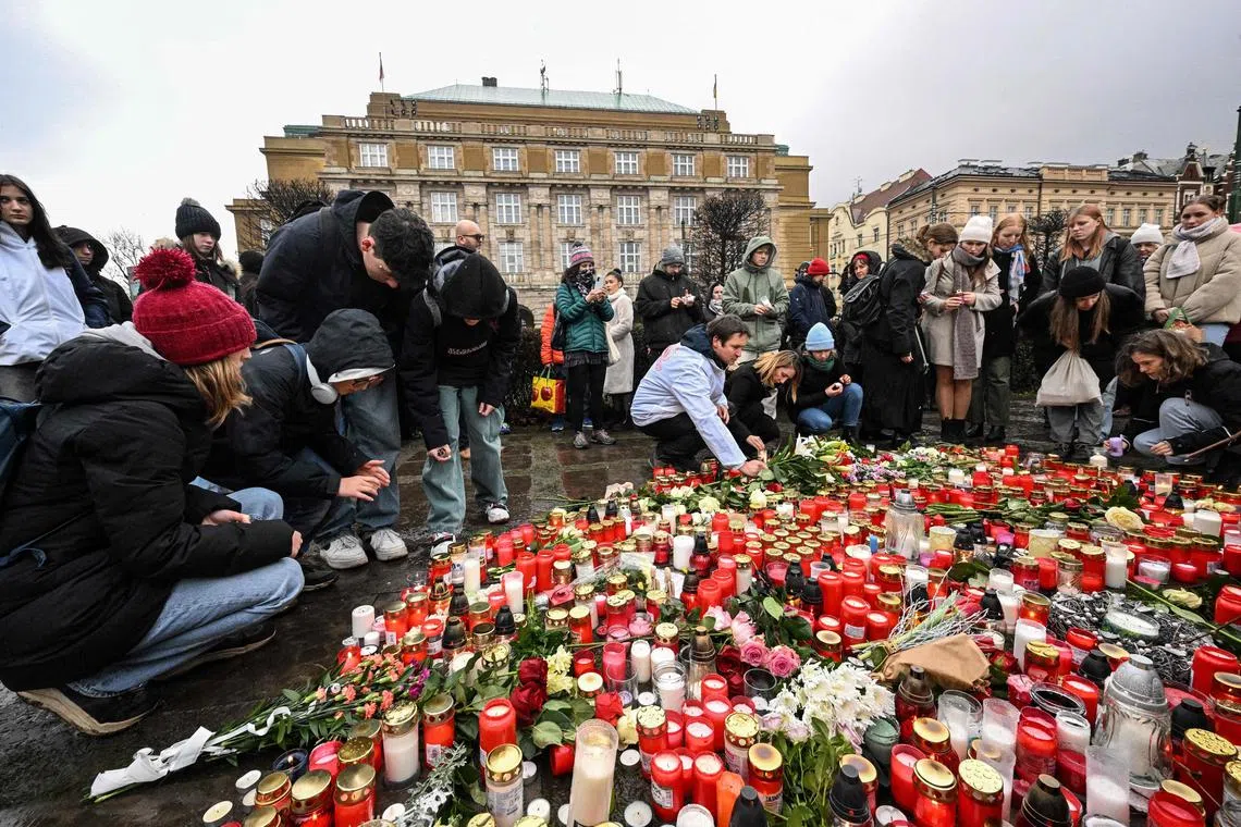 People place candles and flowers at a makeshift memorial for victims of the shooting, at Charles University in Prague.