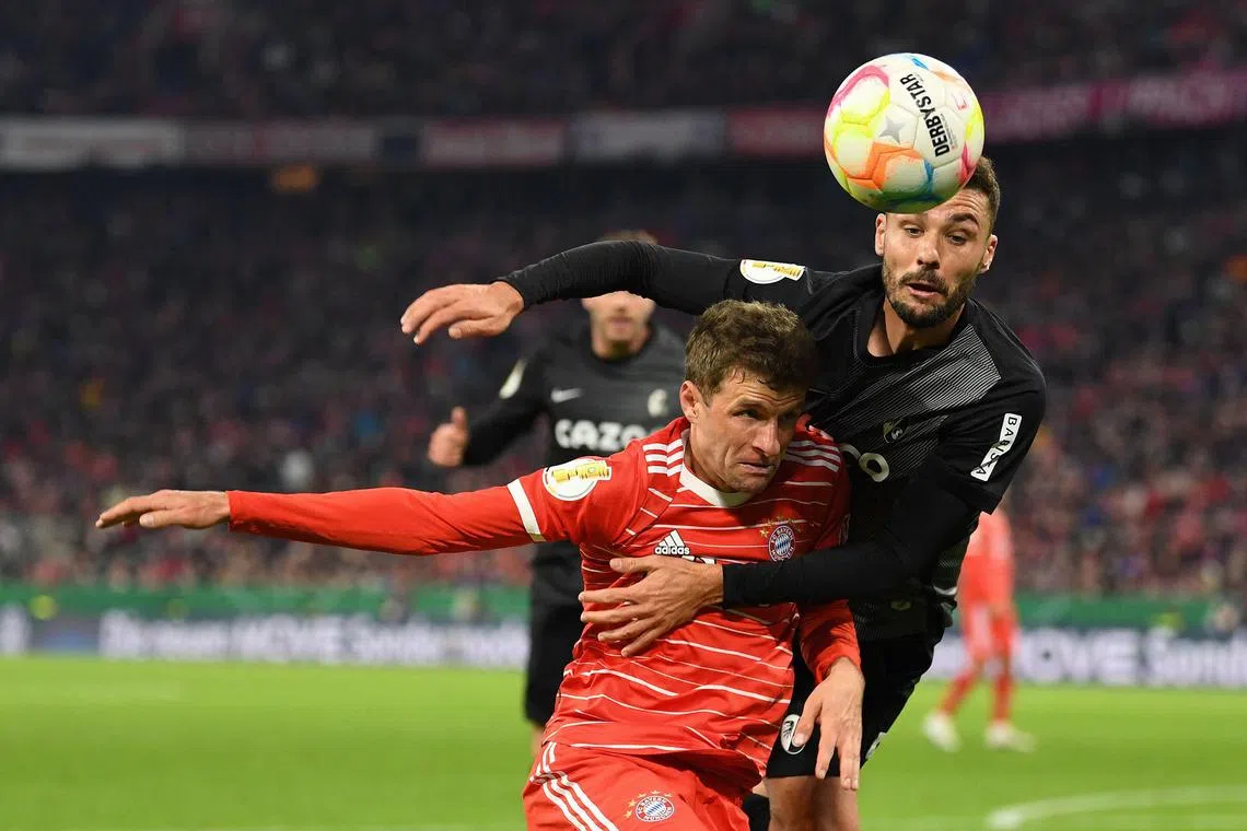 Bayern Munich forward Thomas Mueller and Freiburg defender Manuel Gulde tussling for the ball during the German Cup quarter-final football match in Munich.