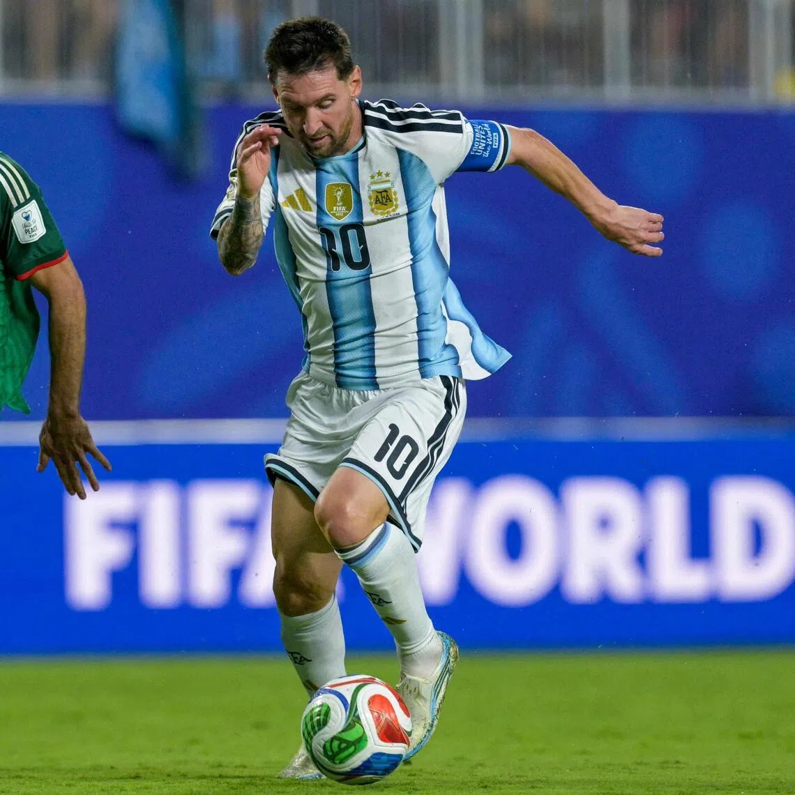Argentina forward Lionel Messi controls the ball before scoring his team's third goal as Algeria defender Rayan Ait-Nouri pursues him during the World Cup holders' 3-0 win on June 16.