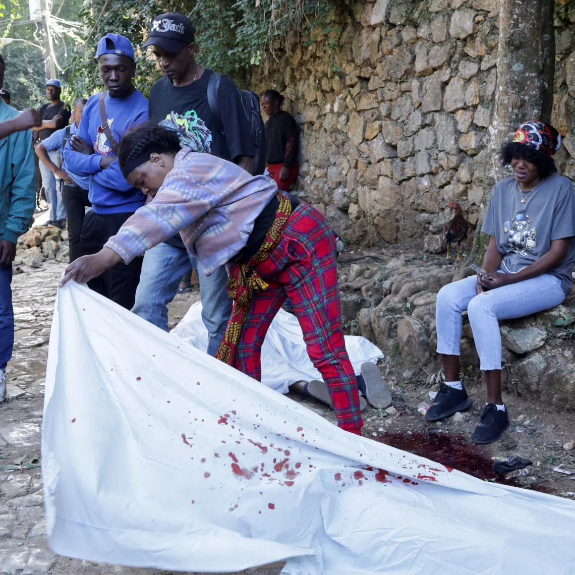A woman lifts a sheet covering the body of a person killed during an overnight raid by an armed gang, on the outskirts of Port-au-Prince, in Kenscoff, Haiti, August 24, 2026. REUTERS/Fildor Pq Egeder