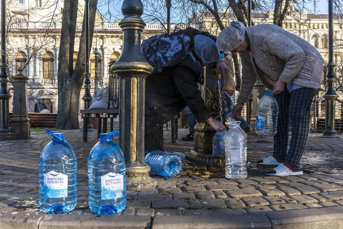 Local residents fill jugs and bottles at a public water well in Kyiv on Oct 31, 2022.