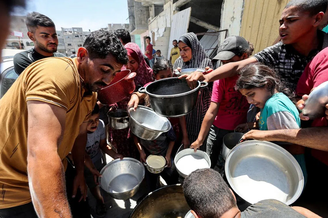 FILE PHOTO: Palestinians gather to receive food cooked by a charity kitchen near houses destroyed in the Israeli military offensive, in Khan Younis in the southern Gaza Strip, May 30, 2024. REUTERS/Ramadan Abed/File Photo