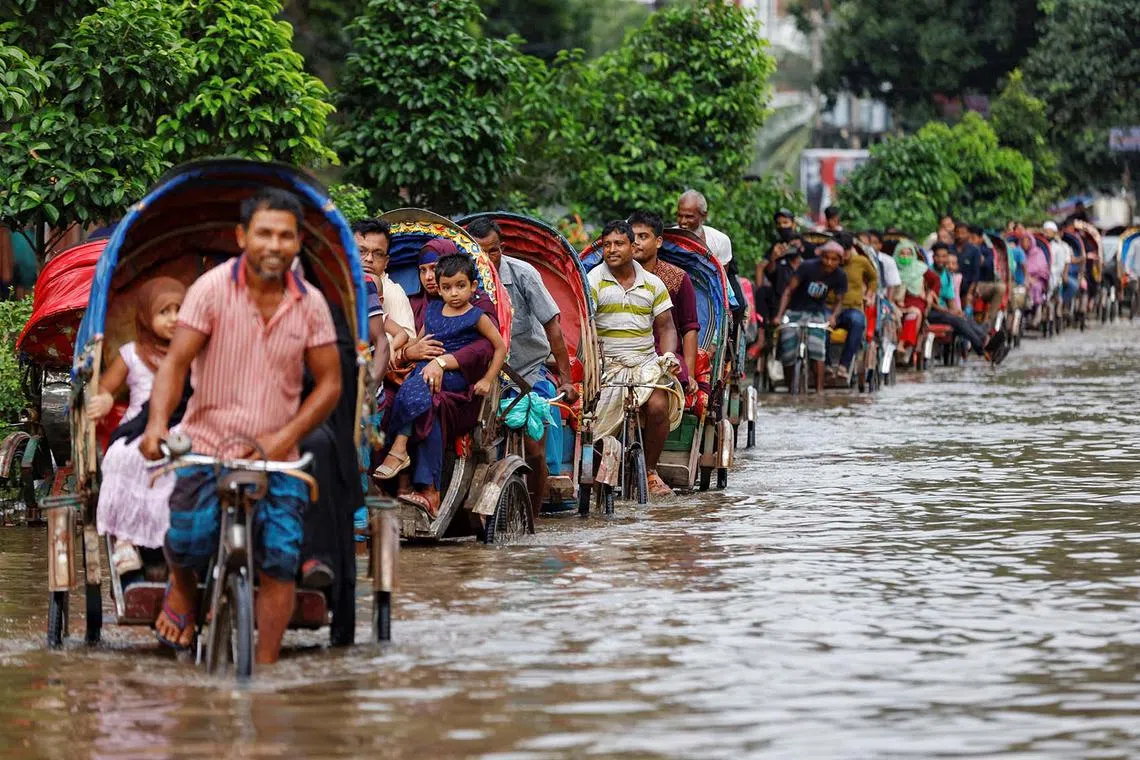 Commuters ride on rickshaws on a flooded road after heavy rains in Dhaka, Bangladesh, Sept 22.