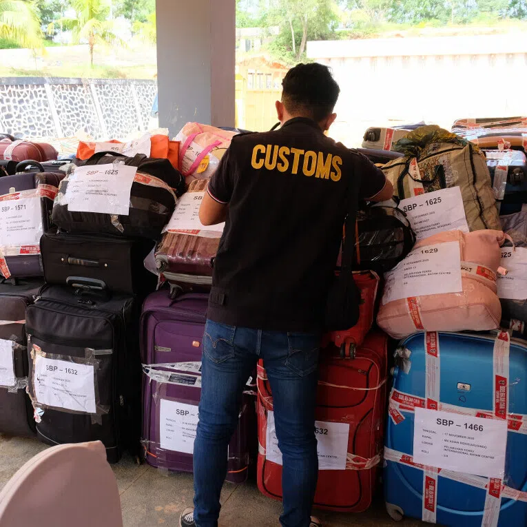 An officer with the Batam Customs and Excise Office inspects luggage containing used clothing on Dec 10.