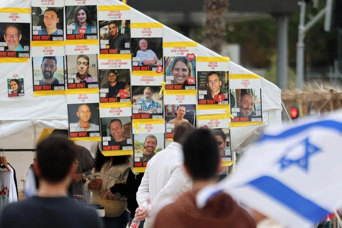 People in Israel's Tel Aviv standing in front of a wall covered with photos of Israeli hostages held captive by Hamas in the Gaza Strip, since the Palestinian militant group's Oct 7, 2023, attack on Israel.