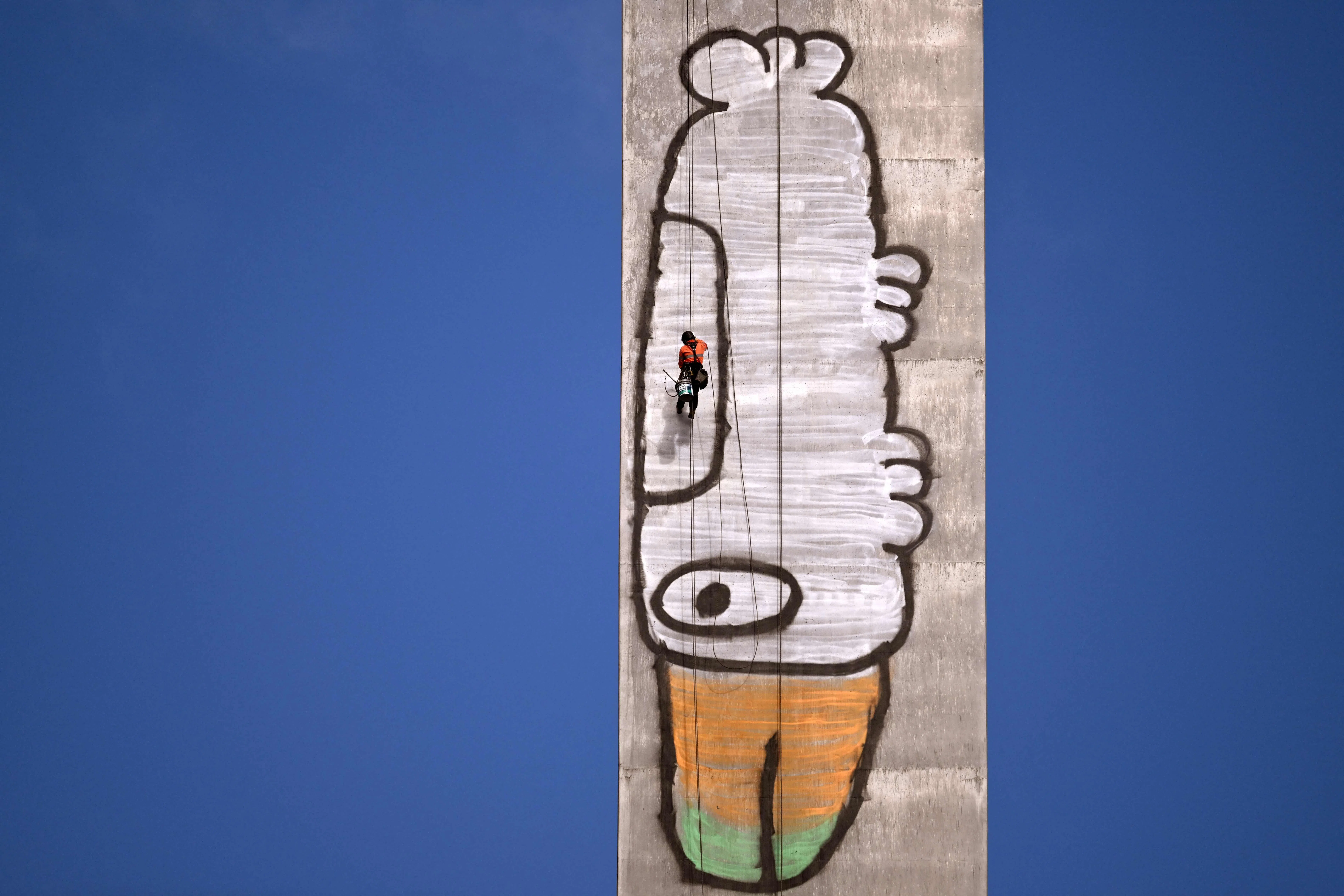 TOPSHOT - Abseilers prepare to paint over Pam the Bird graffiti on Melbourne's Bolte Bridge on July 23, 2026. The graffiti was spray-painted on one of the bridge's 140-metre-tall pylons by alleged vandal Jack Gibson-Burrell and it is expected to take several days, taking 100 litres of surface preparation, primer and paint. (Photo by William WEST / AFP)