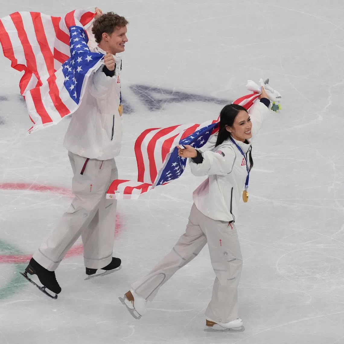 Feb 8, 2026; Milan, Italy; Madison Chock and Evan Bates of the United States of America celebrate after winning gold in the figure skating team event during the Milano Cortina 2026 Olympic Winter Games at Milano Ice Skating Arena. Mandatory Credit: Amber Searls-Imagn Images