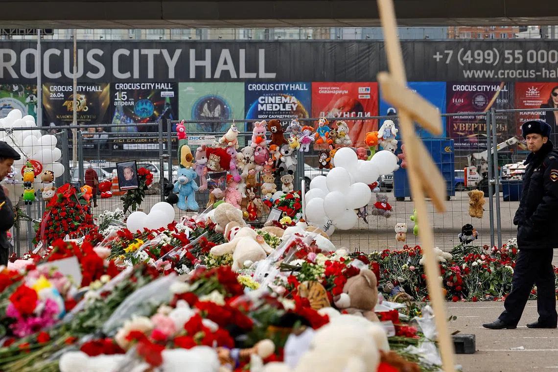 A police officer stands guard next to a makeshift memorial near the Crocus City Hall following a deadly attack on the concert venue outside Moscow, Russia, March 26, 2024. REUTERS/Evgenia Novozhenina