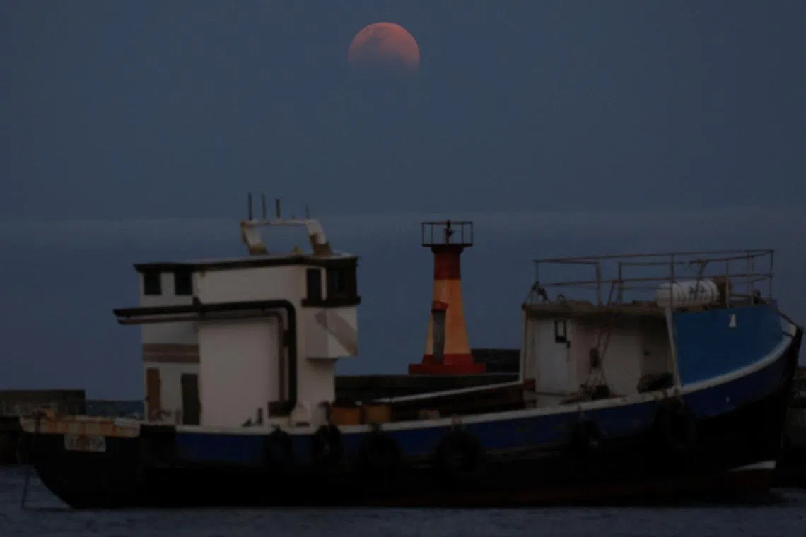 A blood moon rises over Kalk Bay harbour on the night of a total lunar eclipse, in Cape Town, South Africa, on Sept 7, 2025.