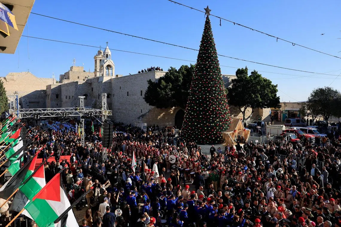 People gather next to the Christmas tree at Manger Square on Christmas Eve, in the Old City of Bethlehem in the Israeli-occupied West Bank.