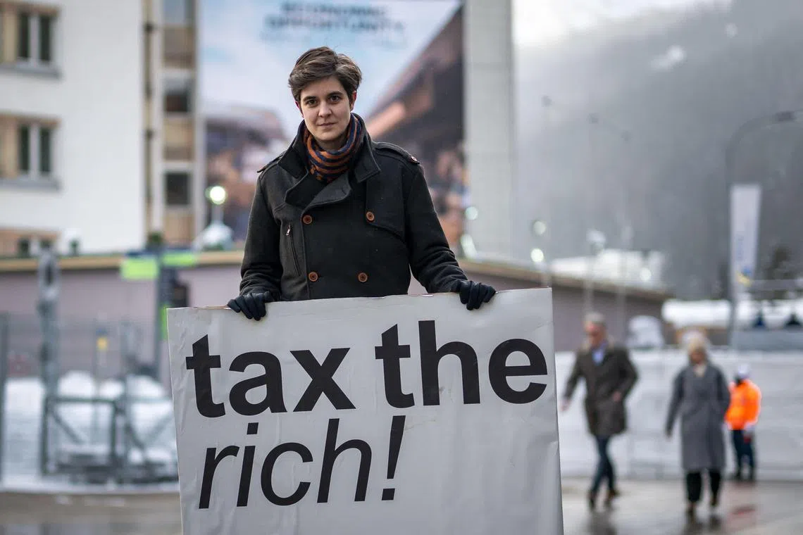 Austrian Marlene Engelhorn, who inherited from her family who owns the Germany's chemical giant BASF, poses with a placard reading "Tax the rich!" at the entrance of the Congress center on the opening of the annual meeting of the World Economic Forum (WEF) in Davos, on January 15, 2024. (Photo by Fabrice COFFRINI / AFP)