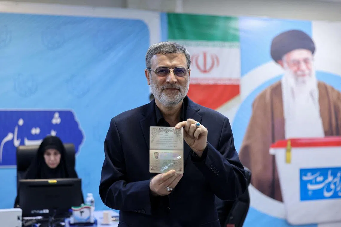 Iranian Amirhossein Ghazizadeh-Hashemi displays a document as he registers his candidacy for Iran's presidential elections at the Interior Ministry in Tehran on June 3, 2024. In the background a portrait of Iran's Supreme Leader Ayatollah Ali Khamenei. (Photo by ATTA KENARE / AFP)