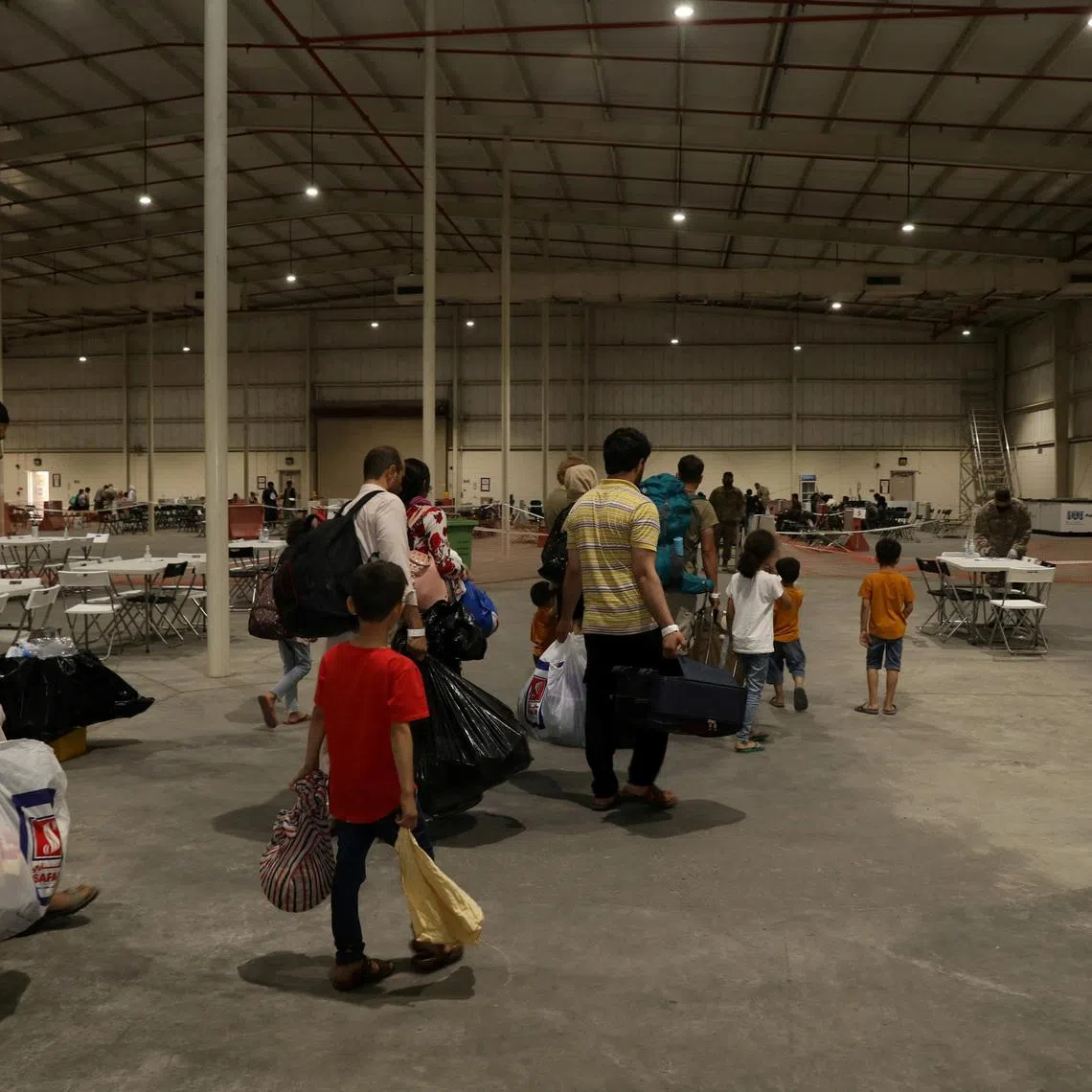 FILE PHOTO: Special Immigrants from Afghanistan walk through the in-processing building after their evacuation at Camp As Sayliyah, Qatar, August 20, 2021. U.S. Army/Sgt. Jimmie Baker/Handout via REUTERS/File Photo