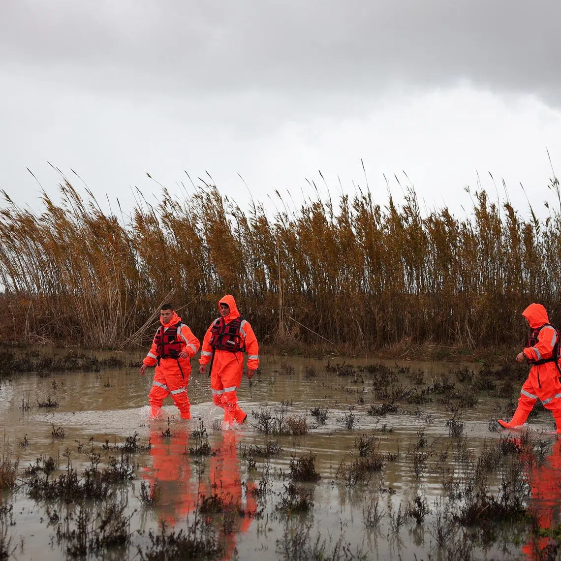 Civil emergency members walk in floodwater, after severe rain caused flooding, near Vjosa river, in Dellenja, near Vlora, Albania, January 8, 2026. REUTERS/Florion Goga