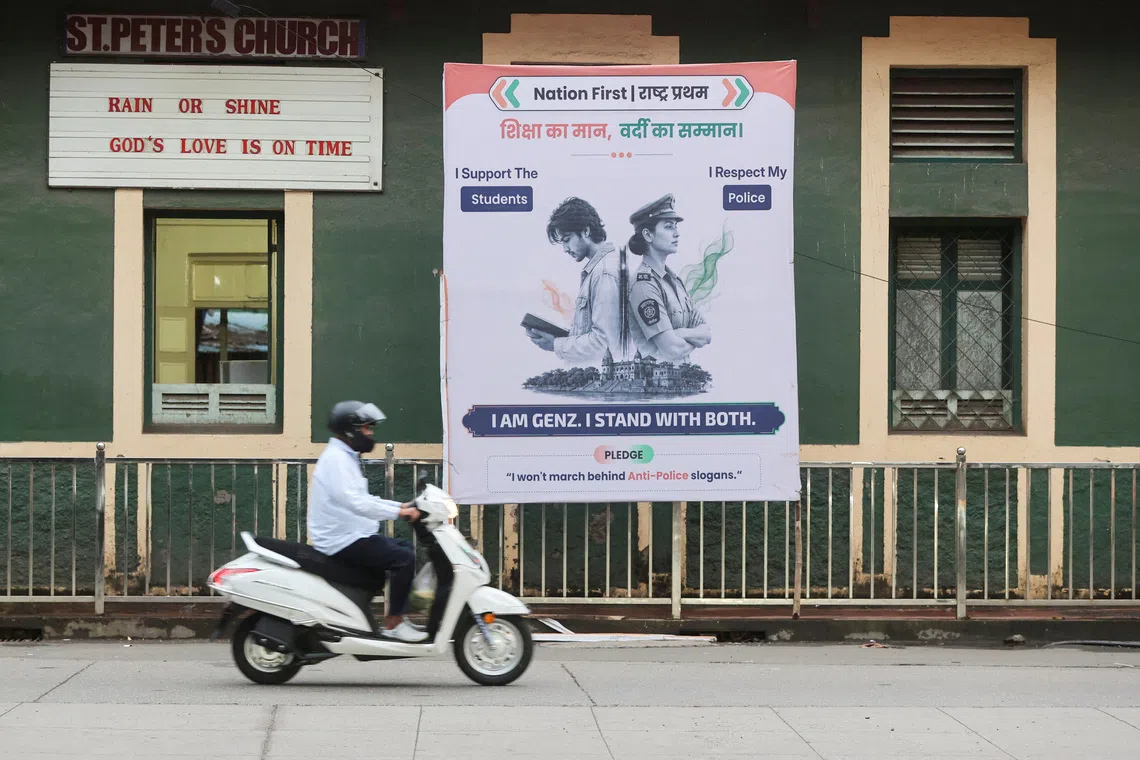 A commuter rides a scooter past a hoarding depicting a student and a police officer along a pavement in Mumbai, India, August 5, 2026. REUTERS/Francis Mascarenhas