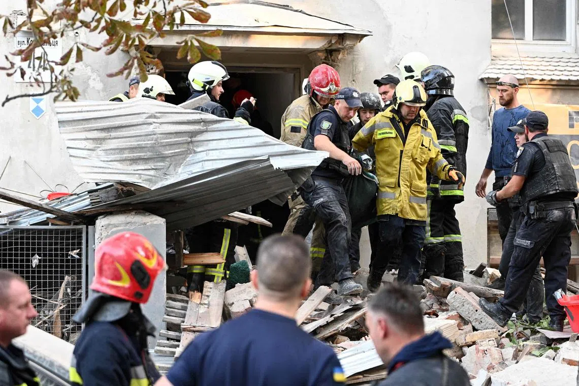 Ukrainian rescuers carrying the body of a person killed in a Russian missile strike, in Lviv, Ukraine, on Sept 4.