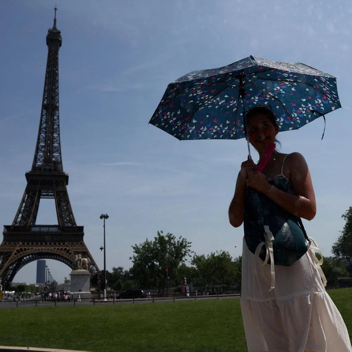 A person shelters under an umbrella by the Eiffel Tower during high temperatures amid a heatwave in Paris, France, June 27, 2026. REUTERS/Tom Nicholson