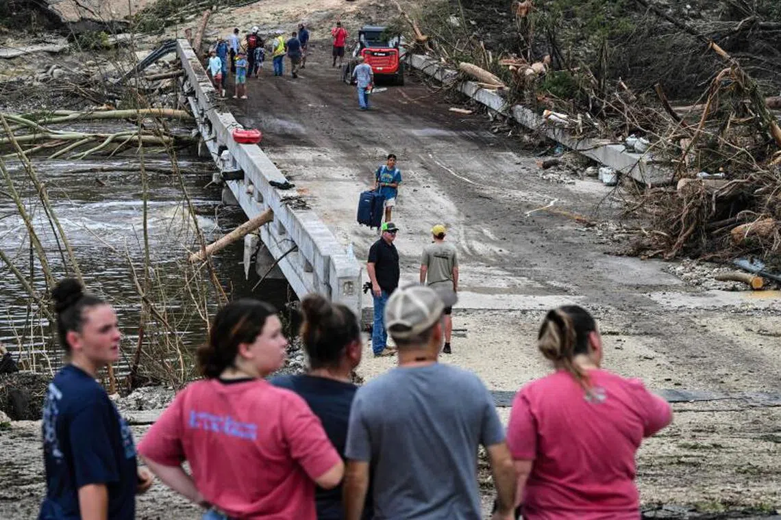 People look on as law enforcement and volunteers continue to search for missing people near Camp Mystic, the site of where at least 20 girls went missing after flash flooding in Hunt, Texas, on July 5, 2025. Rescuers were on Saturday searching for more than 20 girls missing from a riverside summer camp in the US state of Texas, after torrential rains caused devastating flooding that killed at least 27 people -- with more rain on the way. "So far, we've evacuated over 850 uninjured people, eight injured people and have recovered 27 deceased fatalities at this time. Of these 27, 18 are adults, nine are children," said Kerr Country Sheriff Larry Leitha on July 5. (Photo by RONALDO SCHEMIDT / AFP)