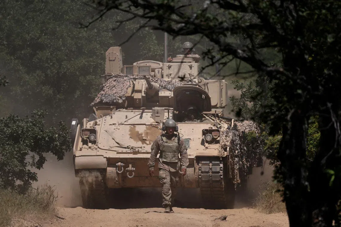 FILE PHOTO: A U.S. soldier walks in front of an armoured vehicle during \"Balkan Sentinel - 25\" military drill, an exercise involving personnel and equipment from the Bulgarian Land Forces and Air Force, formations from the NATO Multinational Battle Group with Italy, and a mechanized platoon from the Romanian Land Forces, in Koren, Bulgaria, June 9, 2025. REUTERS/Stoyan Nenov/File Photo