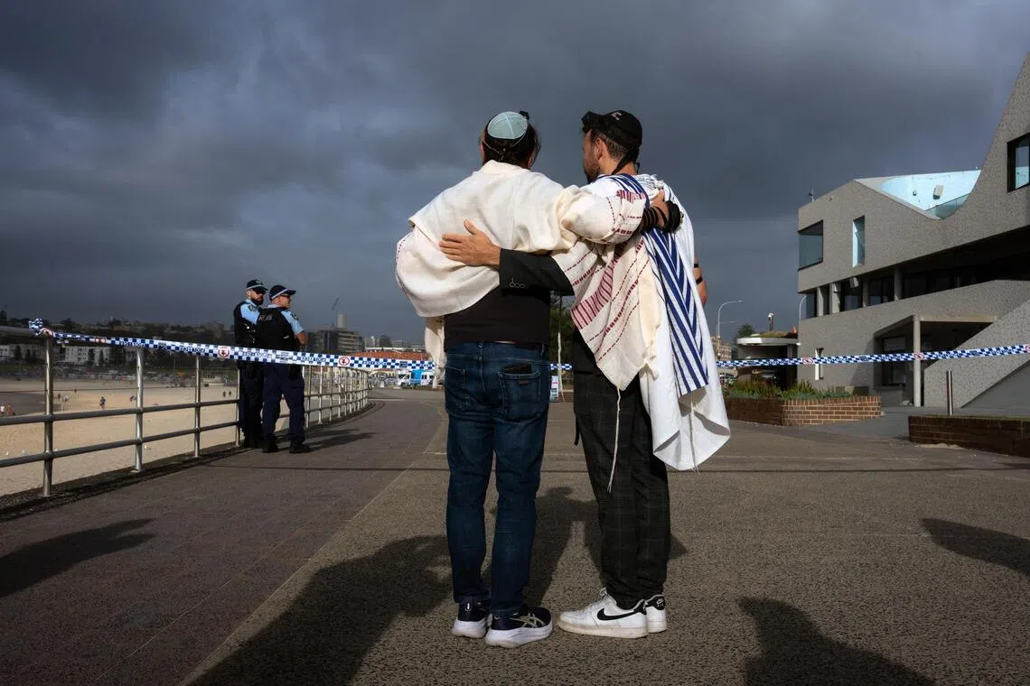 Jewish men embracing after morning prayer at the site of the deadly shooting attack at Bondi Beach in Sydney on Dec 15.
