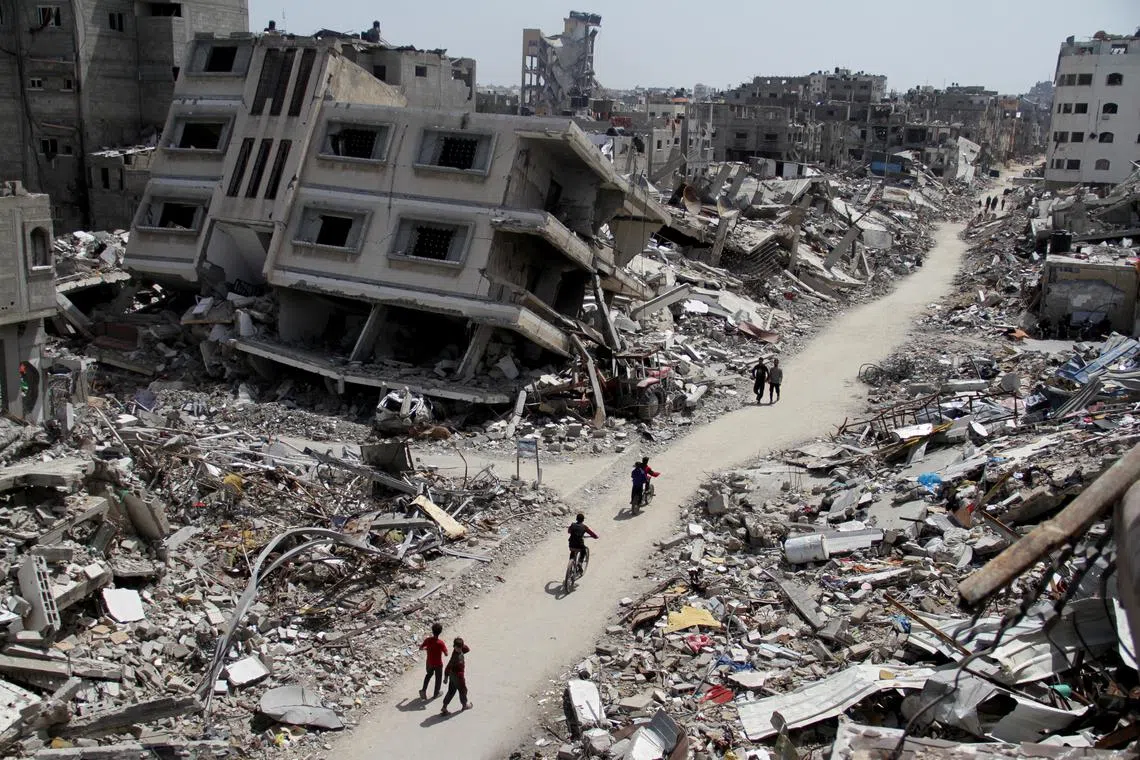 Palestinians ride bicycles past the ruins of houses and buildings destroyed during Israel’ military offensive, amid the ongoing conflict between Israel and the Palestinian Islamist group Hamas, in the northern Gaza Strip March 31, 2024. REUTERS/Mahmoud Issa