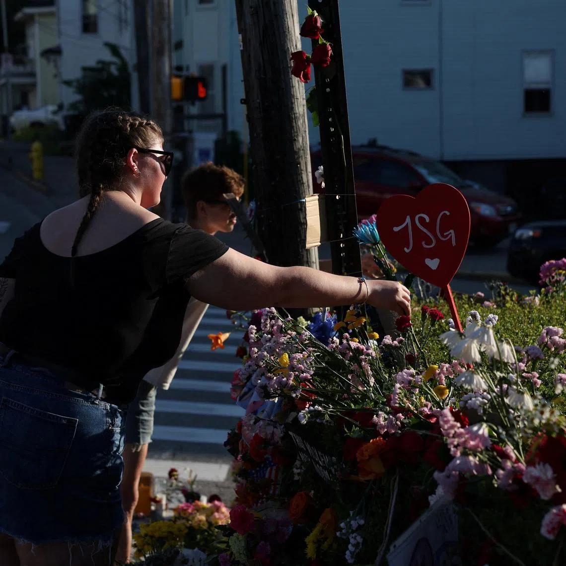 A woman places a flower at a makeshift street-side memorial for Johan Sebastian Duran, a driver who was fatally shot on July 13 by US ICE agents.