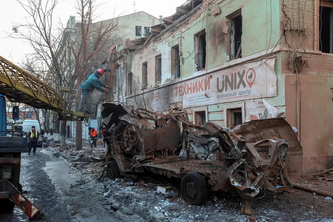 Municipal workers remove debris at the site of a Russian missile strike, in central Kharkiv, Ukraine.