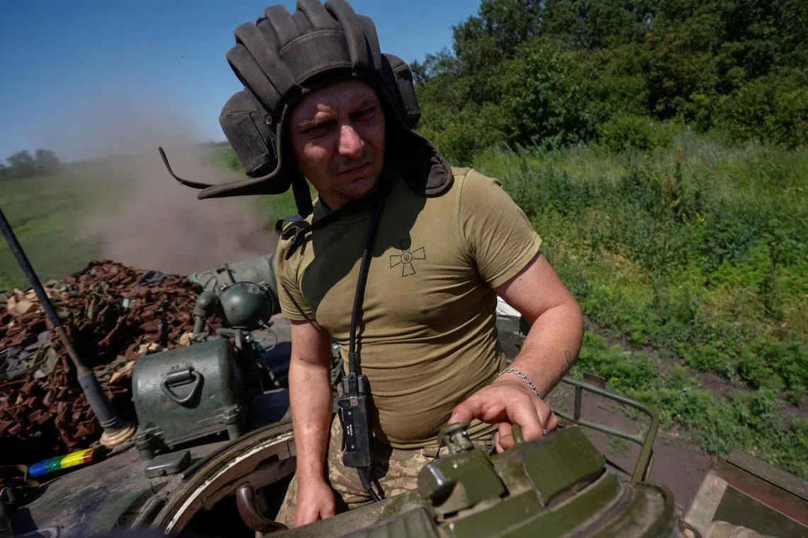 A Ukrainian serviceman rides in a T-80 main battle tank captured earlier from Russian troops, in a field near the front line town of Bakhmut, Ukraine.